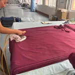 iron-process Worker ironing fabric in the finishing area