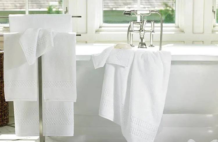 White bath towels hanging beside a bathtub