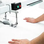 Industrial sewing machine stitching white bedding